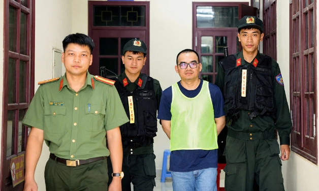 Lực lượng chức năng dẫn giải đối tượng cầm đầu đường dây tại Việt Nam - Đinh Đức Phụng (biệt danh Simon) về cơ quan điều tra. 